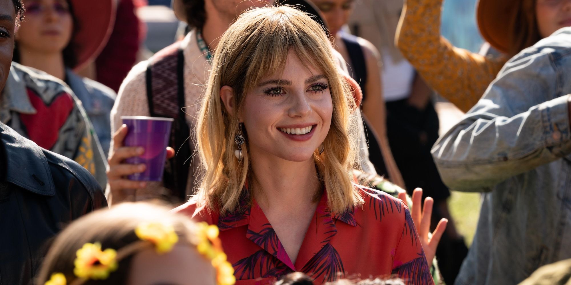 Lucy Boynton smiles while in a crowd in The Greatest Hits movie still