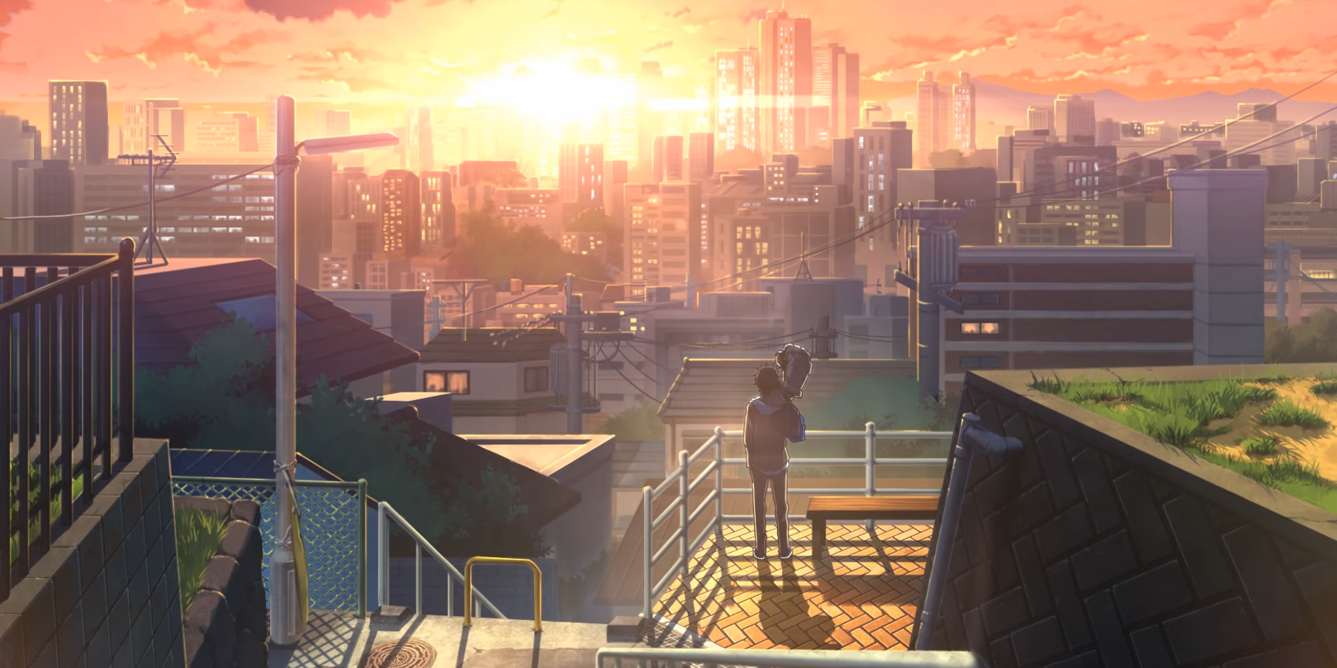 Scenery shot of Mecha-Ude, showing the distant figures of Hikaru and Alma standing on a hilly section of a Japanese City, with the sun setting in the distance between several high rises.
