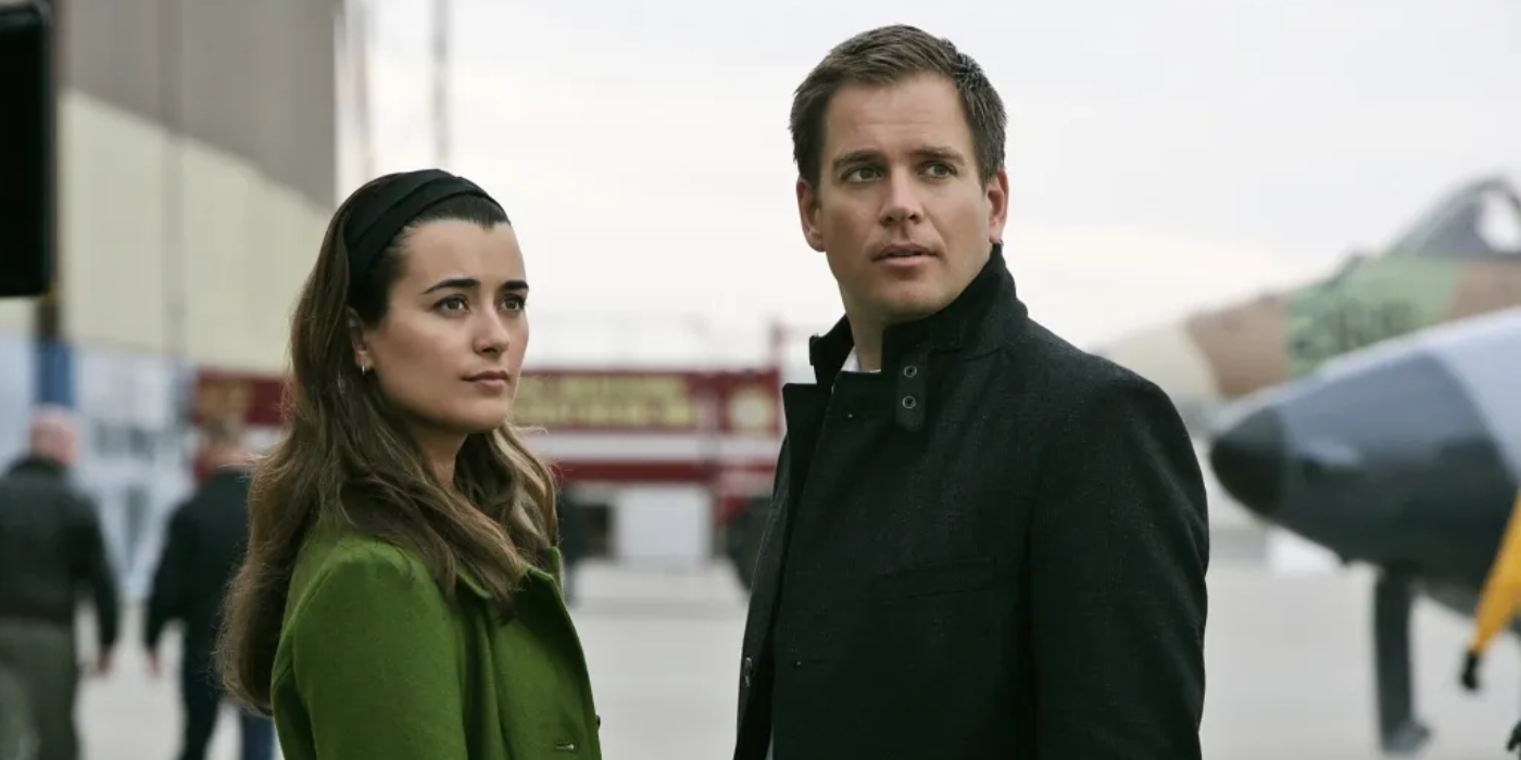 Tony and Ziva stand on an airport tarmac and look offscreen in NCIS