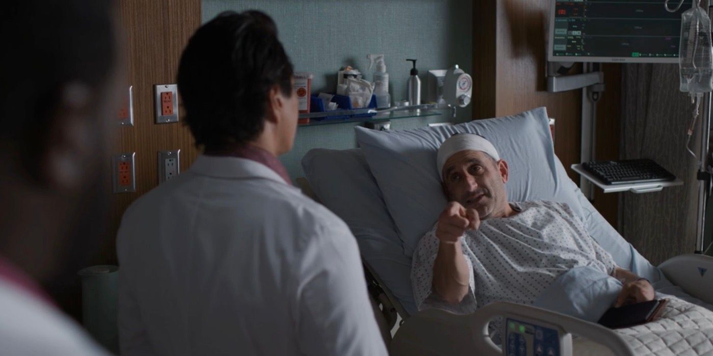 Peter Jacobson lying in the hospital bed and pointing at the doctor.