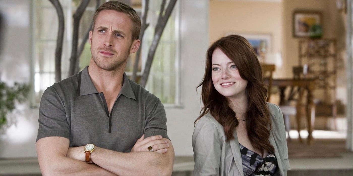 Ryan Gosling está com os braços cruzados e Emma Stone fica ao lado dele sorrindo.