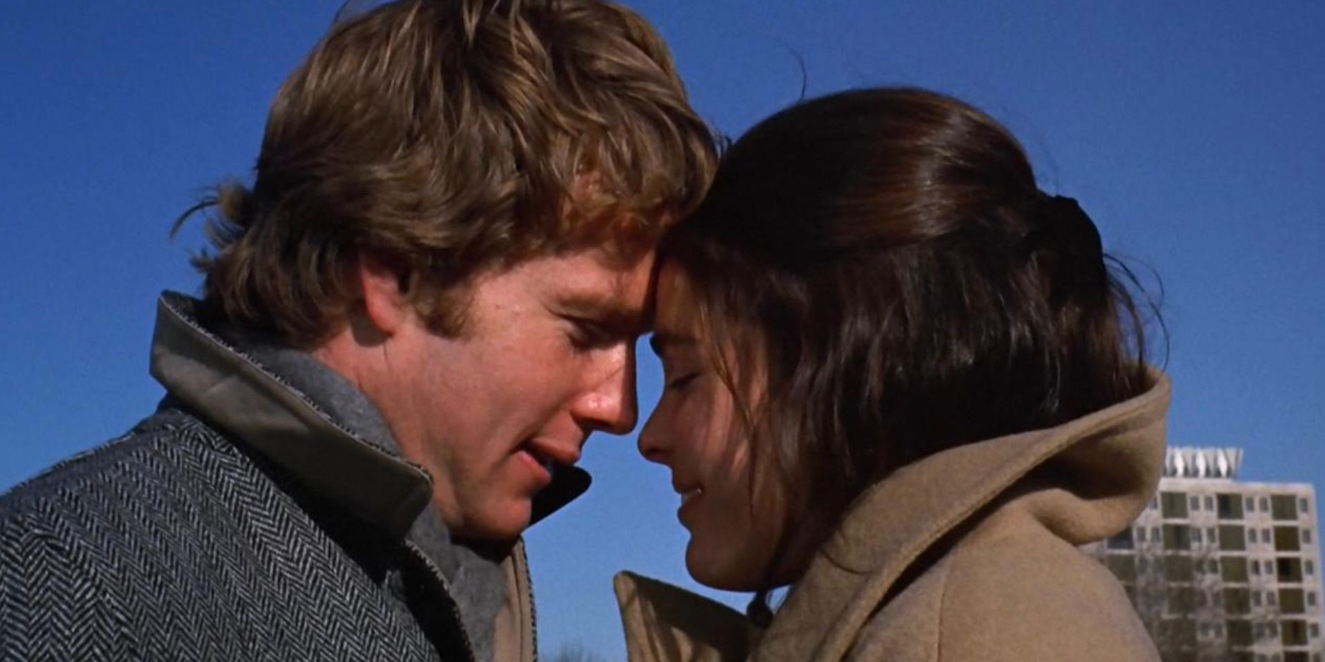 Ryan ONeal and Ally McGraw wearing coats and smiling with their foreheads pressed together in the 1970 movie Love Story