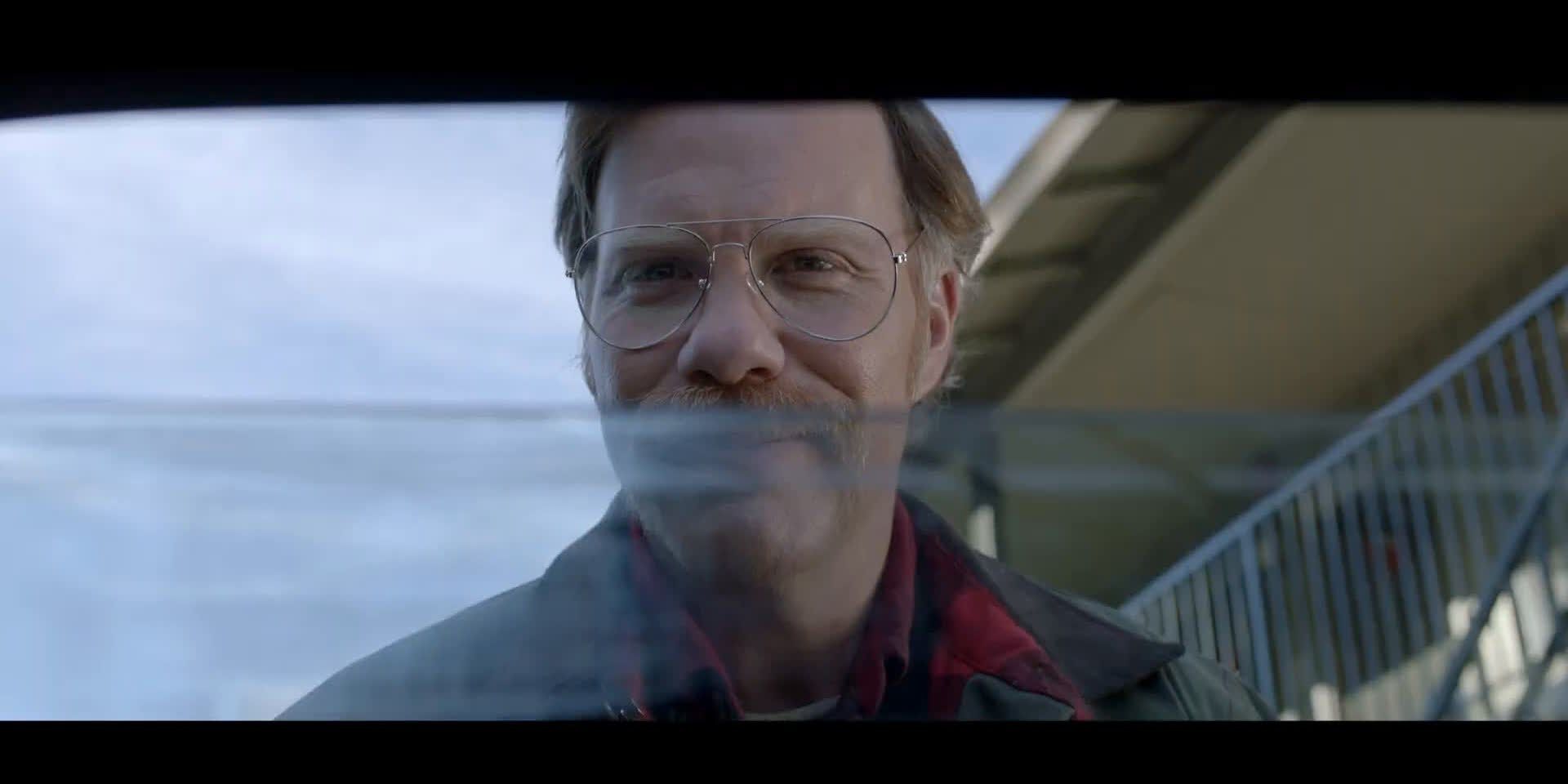 Sam (Marc Menchaca) wears glasses while looking into a car through the half-cracked window in Alone (2020).