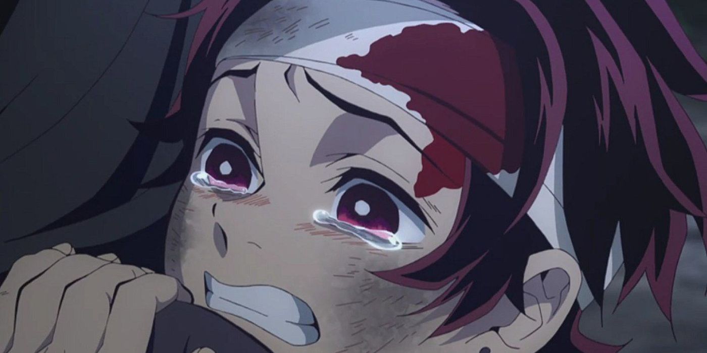 Tanjiro crying in Demon Slayer with a bloody bandage on his forehead and scuffed cheeks.
