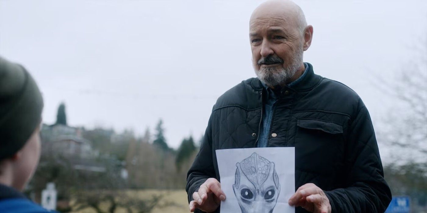 Terry O'Quinn as Peter Buck holding an alien painting in Resident Alien