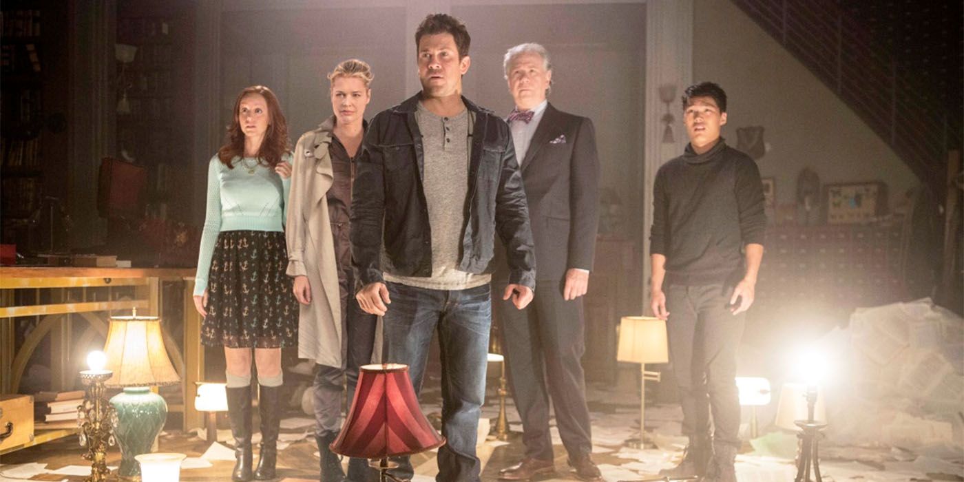 The Librarians cast standing together in a living room