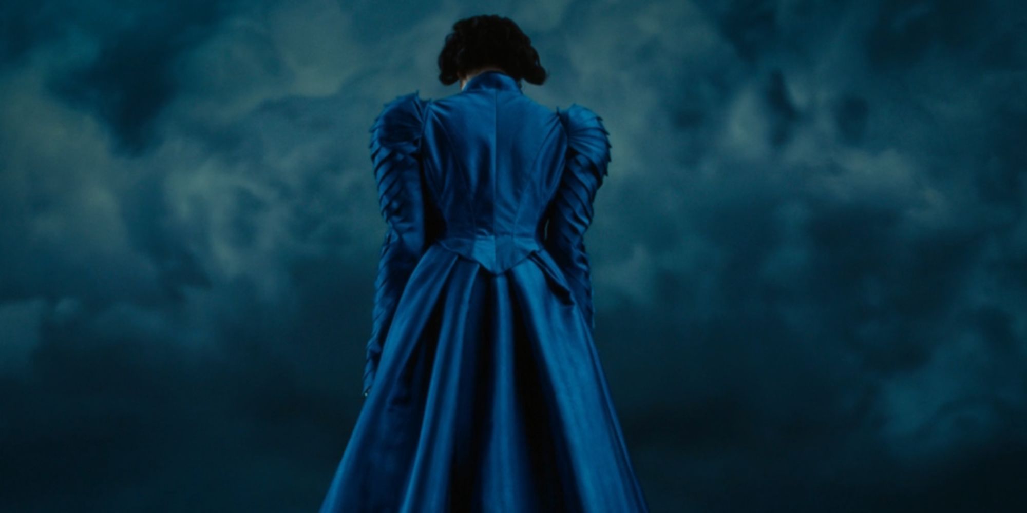 Emma Stone as Victoria Blessington with her back to the camera in a blue dress in Poor Things