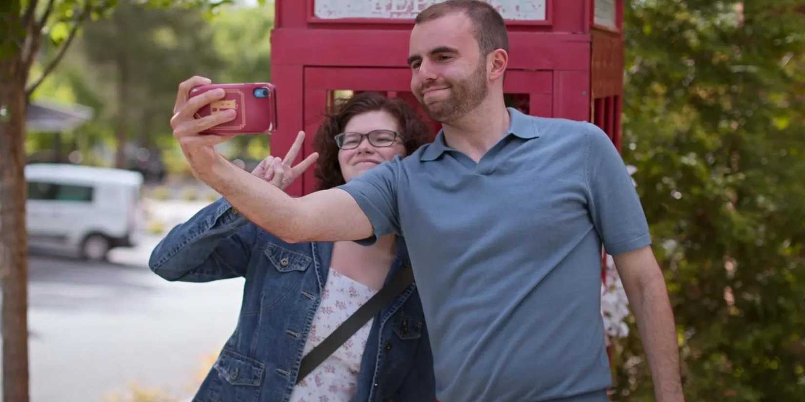 love on the spectrum connor tomlinson and emma take a selfie in front of a red phone booth