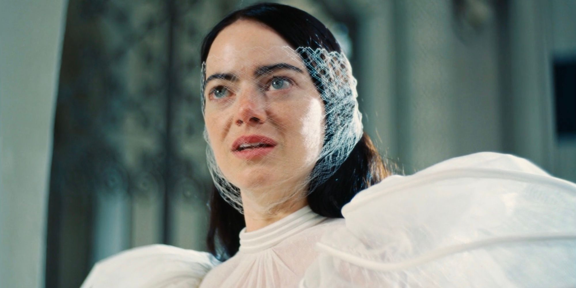 Bella Baxter (Emma Stone) wears a lace veil over her face on her wedding day in Poor Things.