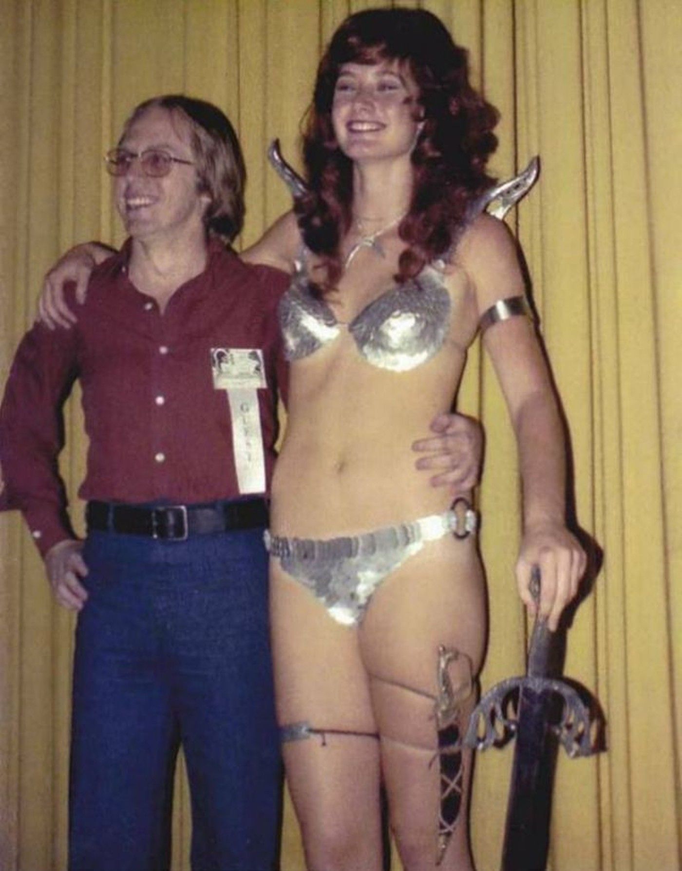 Image of Wendy Pini, cosplaying as Red Sonja, standing next to writer Roy Thomas.
