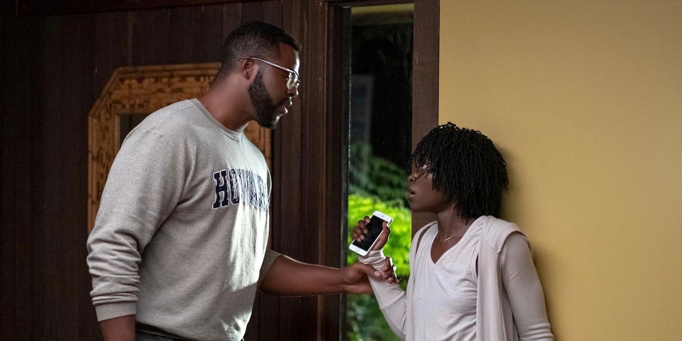 Winston Duke is holding onto Lupita Nyong'o as they stand in front of one another.