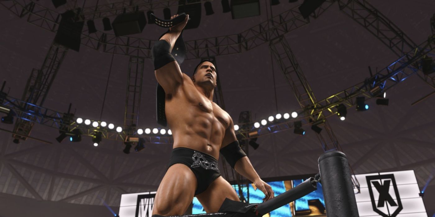 Dwayne 'The Rock' Johnson em pé na corda do meio segurando um cinto no WWE 2K24