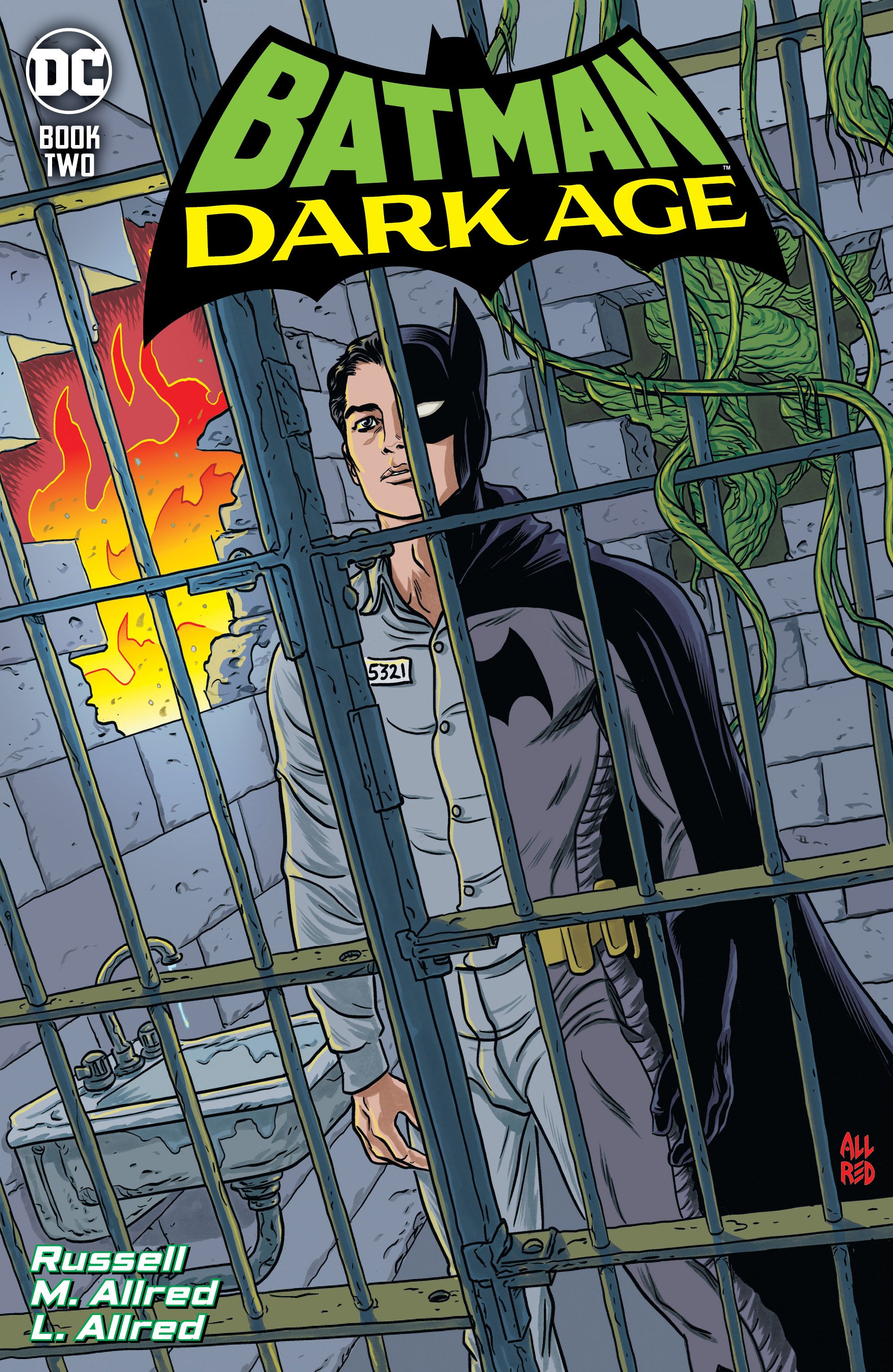 Bruce Wayne standing in a jail cell wearing half a prison jumper and half of a batsuit.