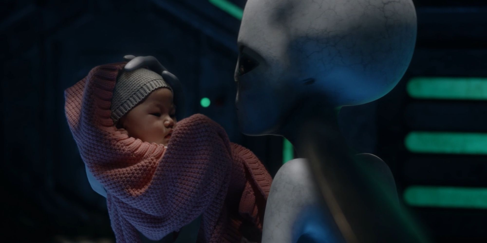 A Grey Alien holding Kate's baby in Resident Alien