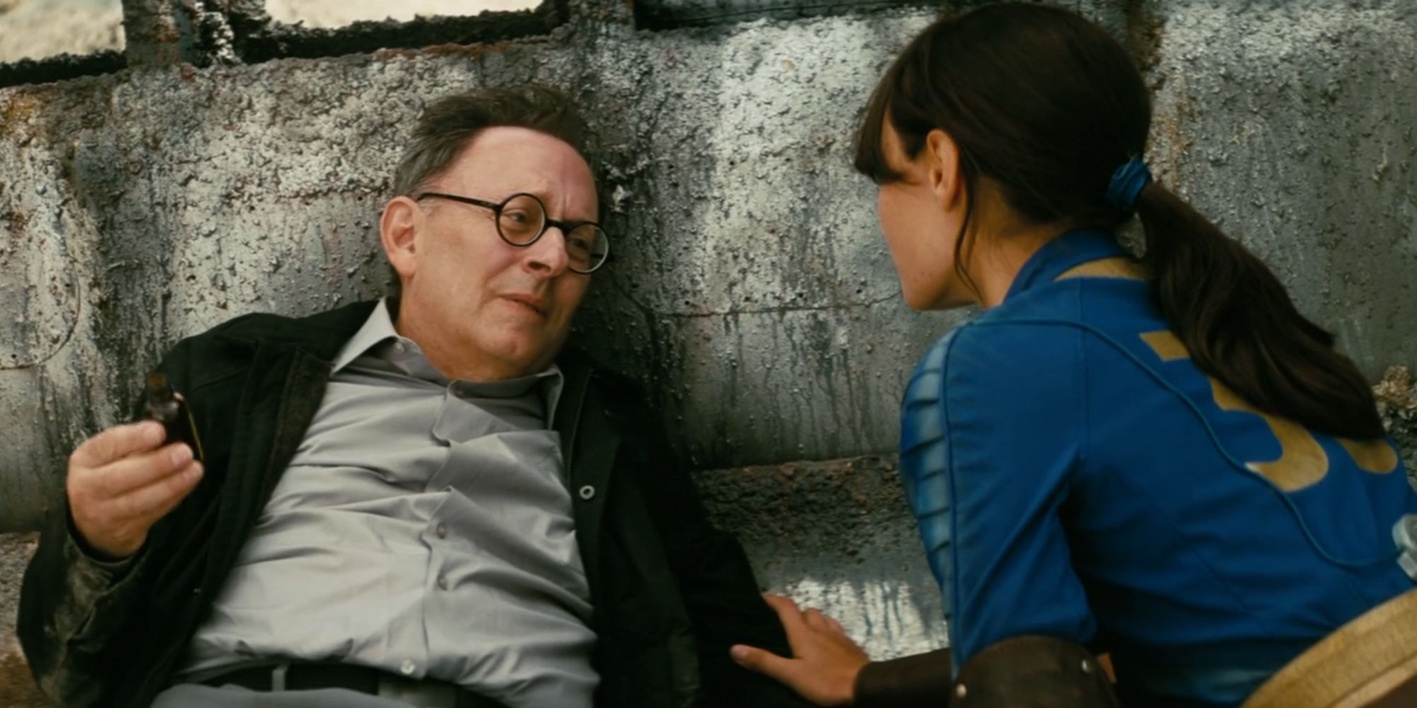 Michael Emerson as Dr. Siggi Wilzig in Fallout lying on the ground with Ella Purnell's Lucy MacLean nearby