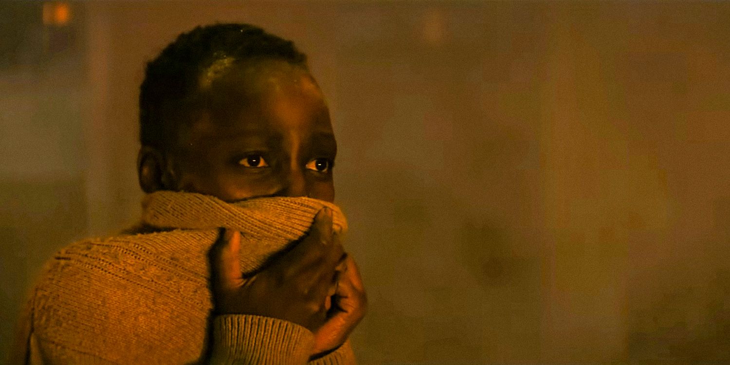 Sam (Lupita Nyong'o) stares into the distance while covering her nose with her sweater in A Quiet Place- Day One Official trailer