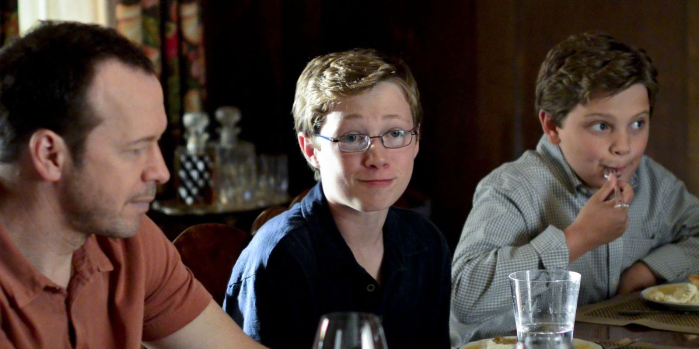 A young Jack Reagan (Tony Terraciano) at the dinner table between his father and brother in Blue Bloods.