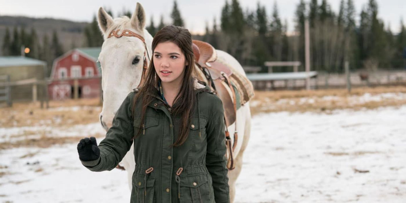 Alisha Newton como Georgie Fleming Morris conduzindo um cavalo pela neve em Heartland.