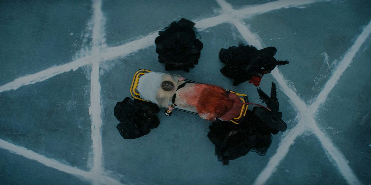 Foto aérea de Anna em uma maca com o vestido encharcado de sangue, cercada pelos Delicates no centro de um desenho de pentagrama em American Horror Story Delicate temporada 12, episódio 9 (FINALE)