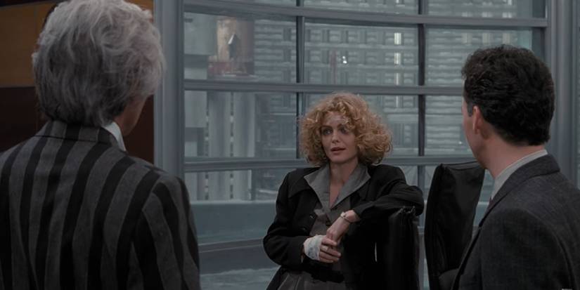 batman returns, michelle pfeiffer as selina kyle talking to max shrek and bruce wayne in an office