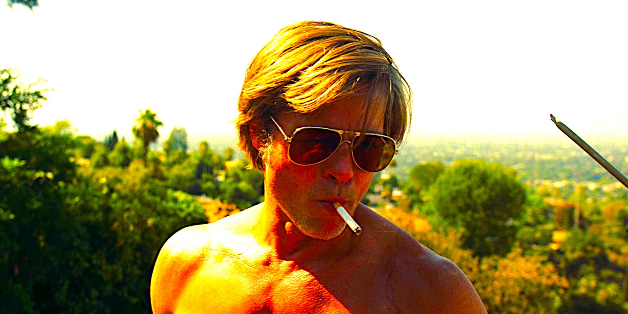 Brad Pitt as Cliff Booth shirtless and wearing sunglasses while smoking a cigarette in Once Upon a Time In Hollywood