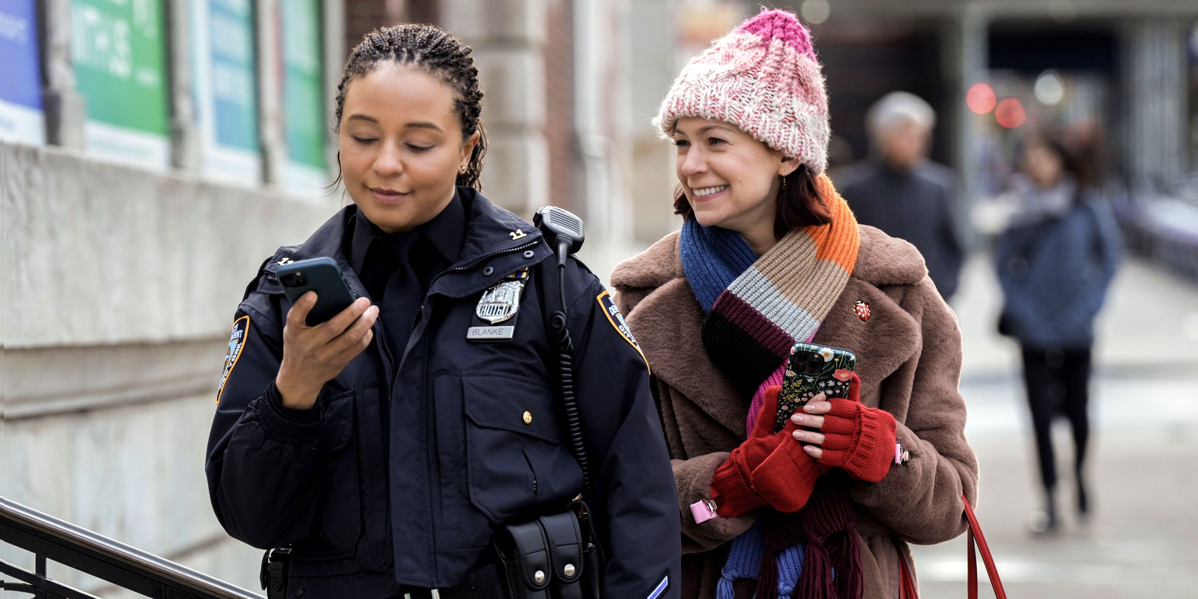 Carrie Preston as Elsbeth holding her phone and smiling at police officer in Elsbeth season 1 episode 6