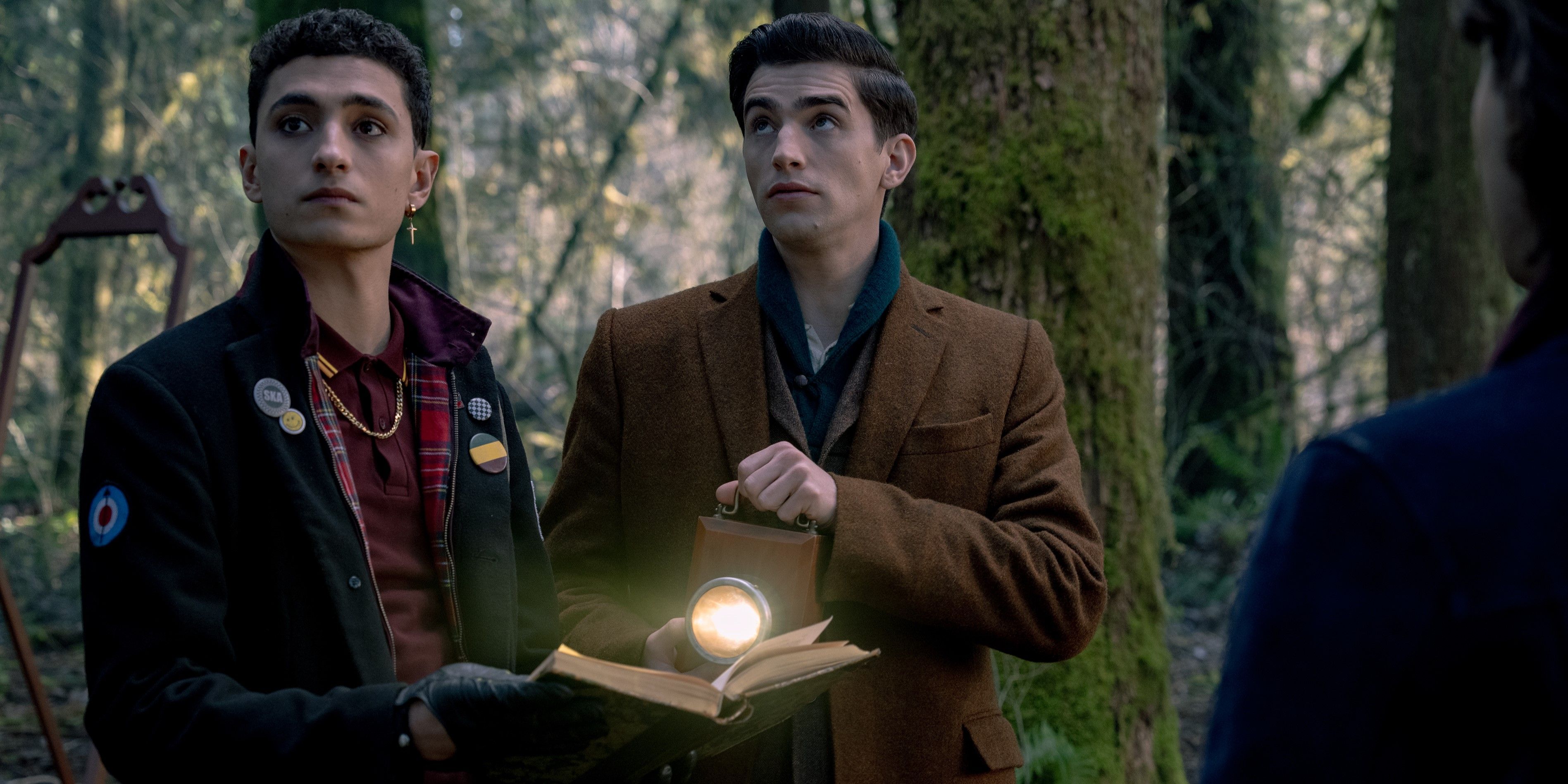 Charles e Edwin olham para um livro na floresta em Dead Boy Detectives