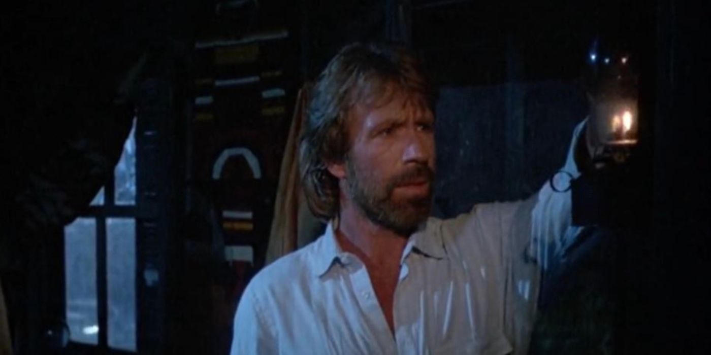 Chuck Norris's Matt holds up a lantern in a cabin from Invasion USA