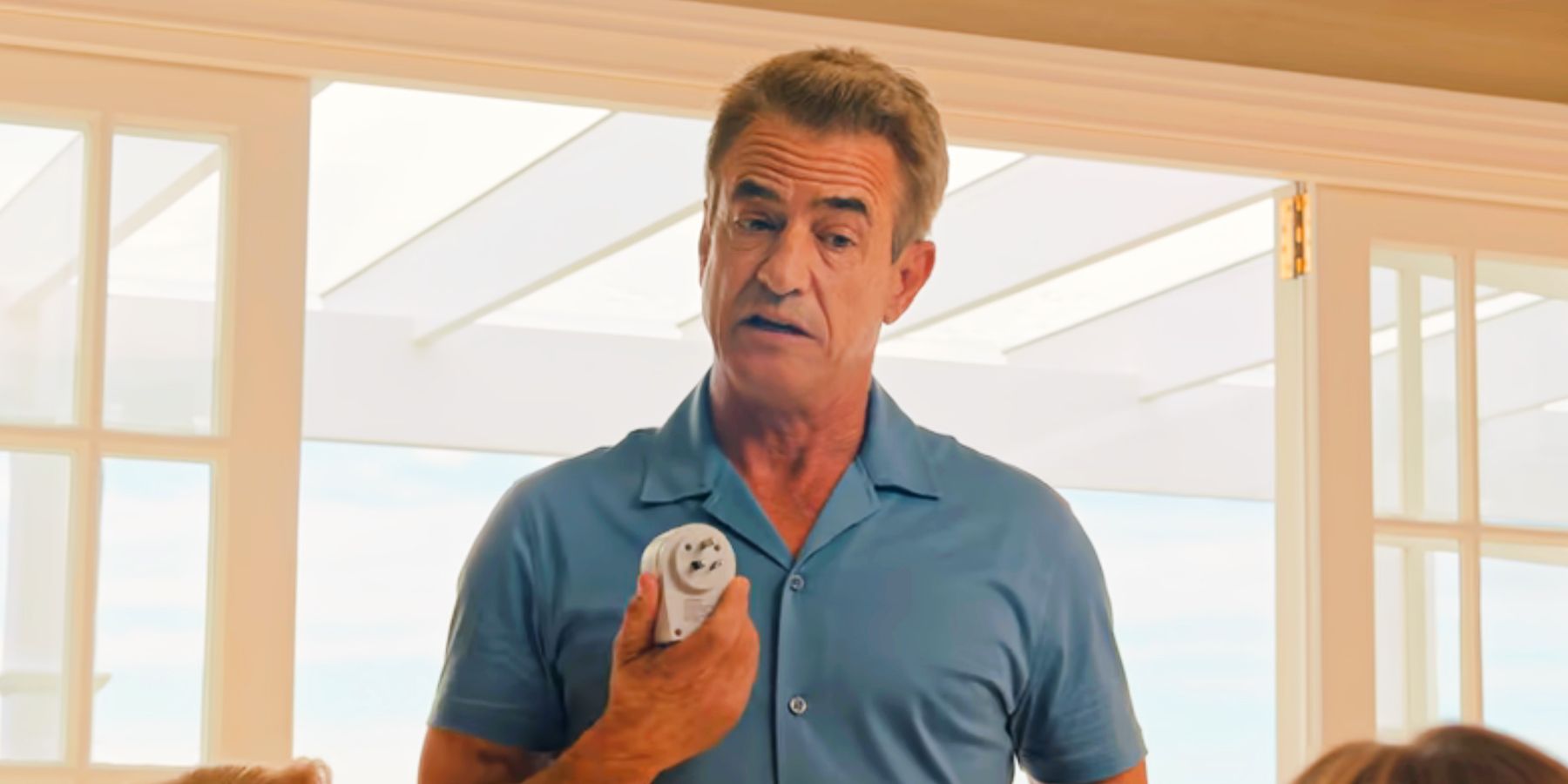 Dermot Mulroney's Leo holding up a plug in Anyone But You