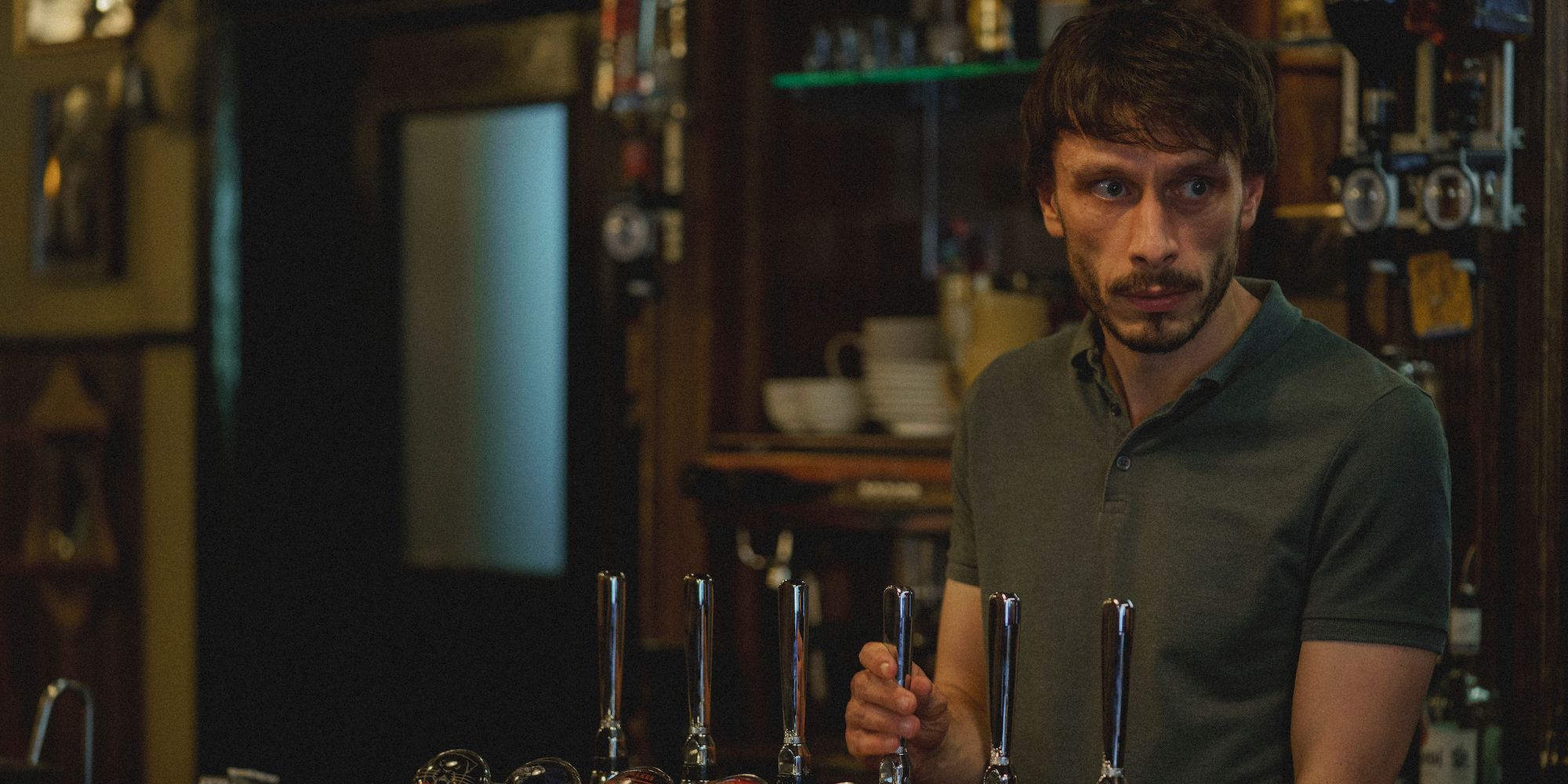 Donny (Richard Gadd) pours beer from the tap behind the bar in Baby Reindeer.