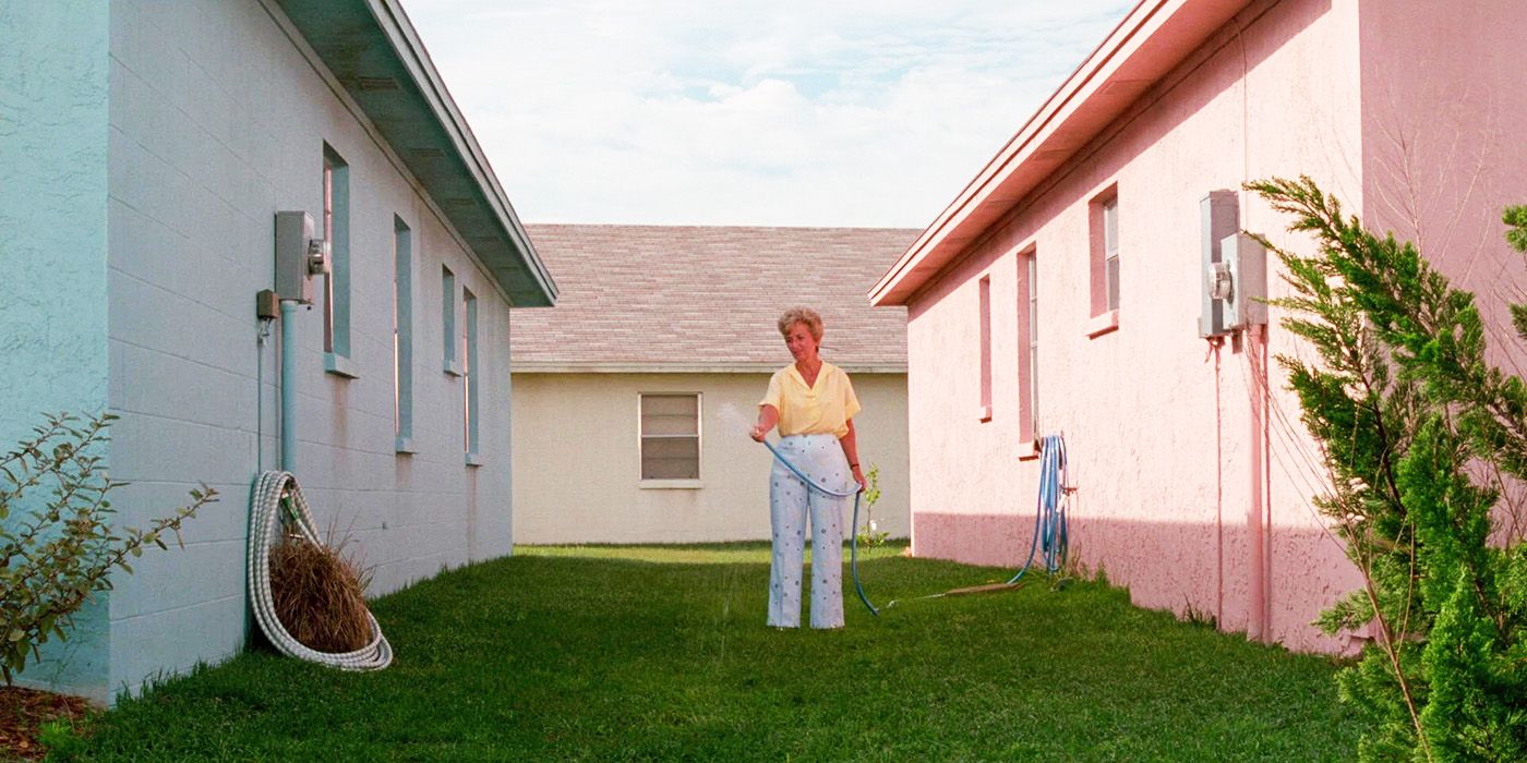 Edward Scissorhands a woman watering the grass between two colorful houses