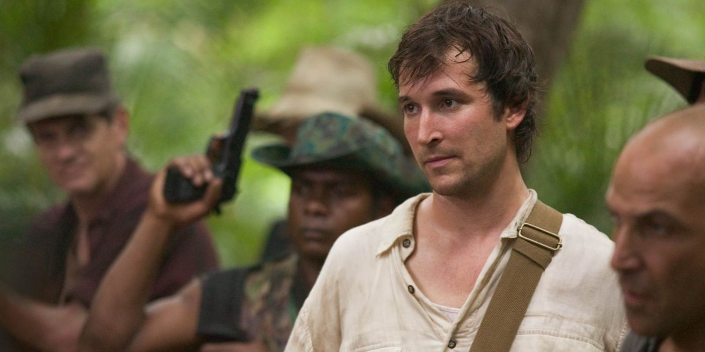 Flynn (Noah Wyle) parecendo nervoso, cercado por homens armados em A Maldição do Bibliotecário do Cálice de Judas.