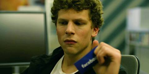 Jesse Eisenberg as Mark Zuckerberg looking sad while holding onto a Facebook card in The Social Network