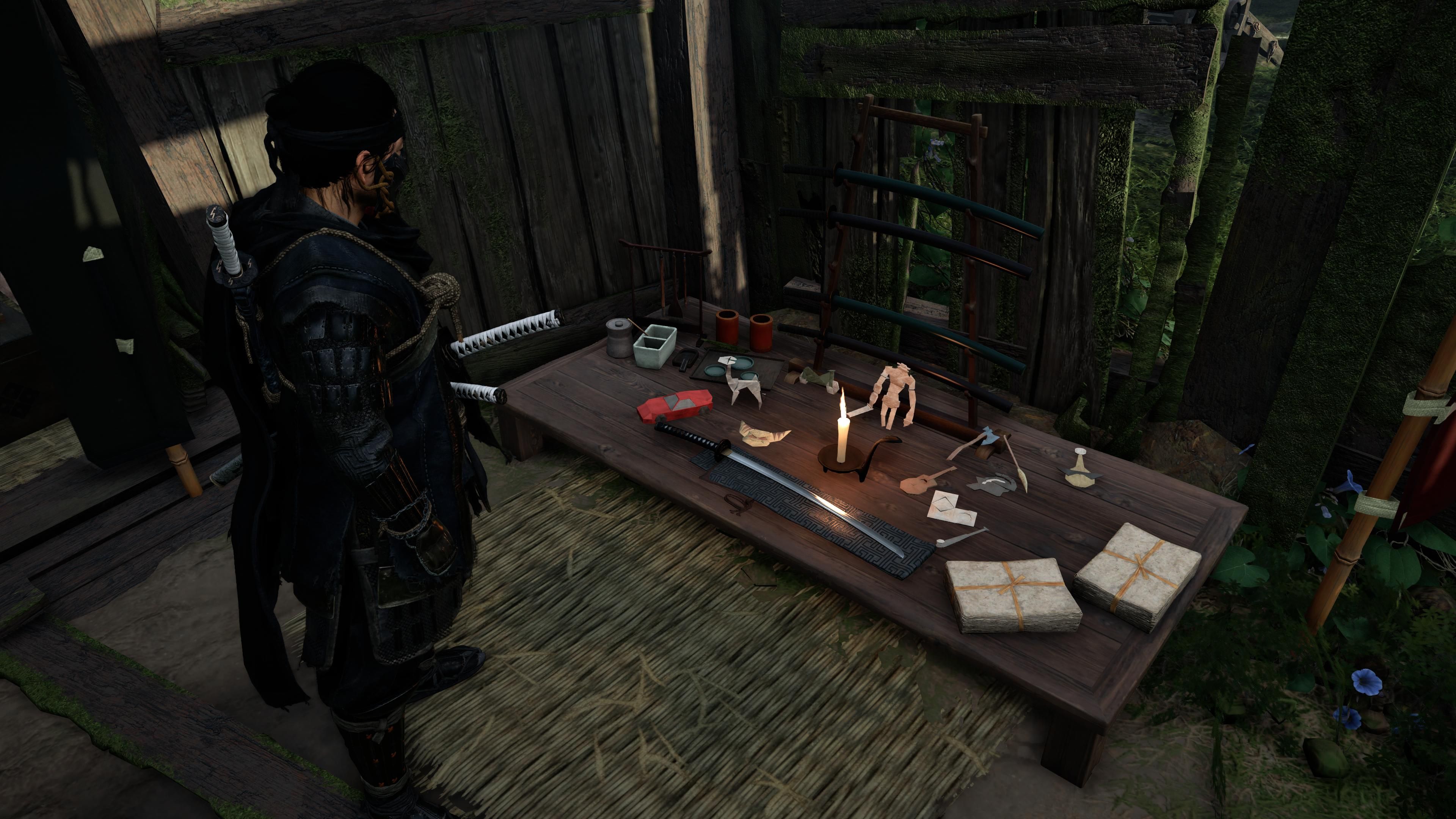 Jin olhando para a mesa com figuras de espada e origami, incluindo pescoço alto de origami, catraca e colosso em Ghost Of Tsushima