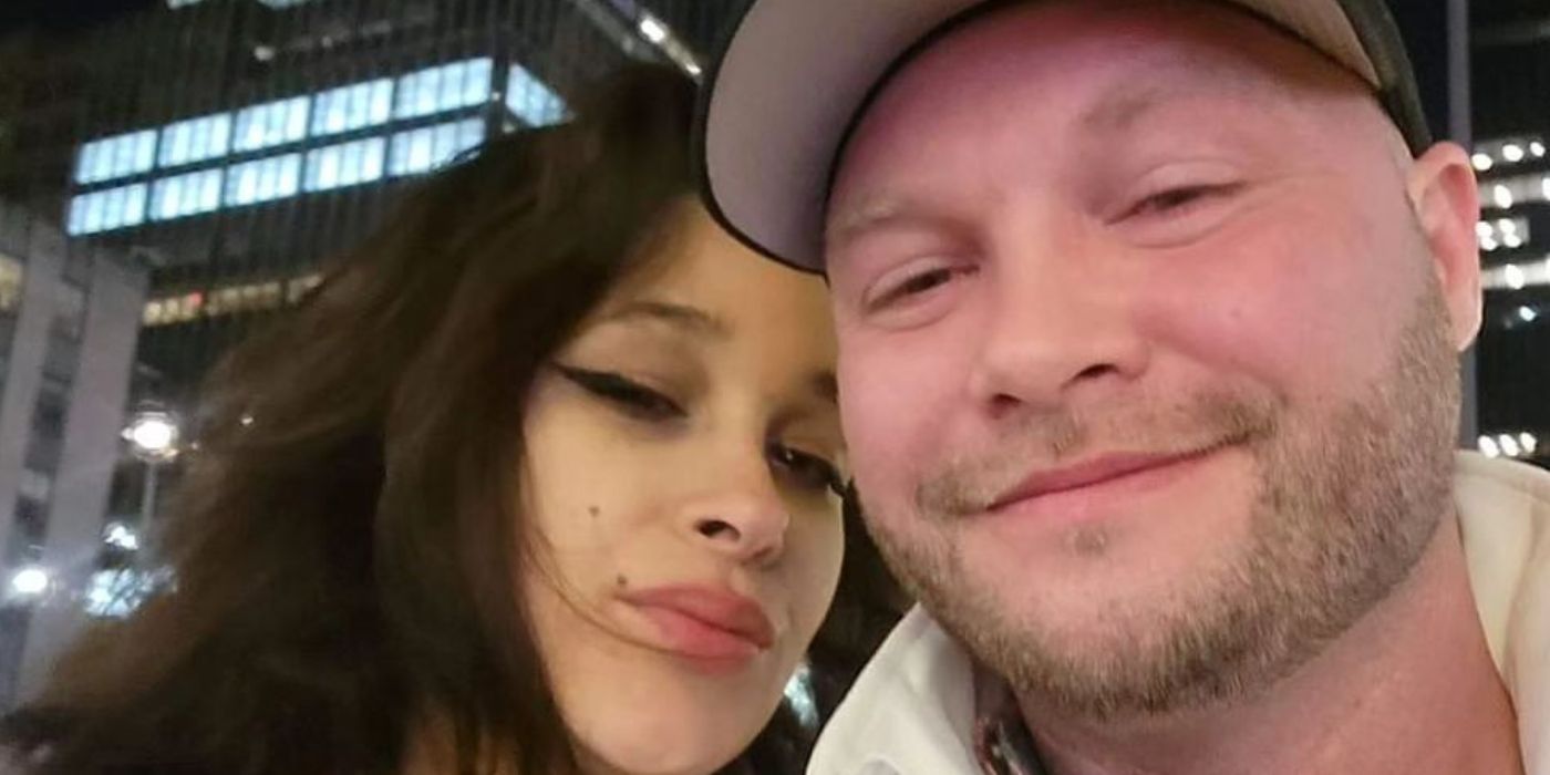 John McManus and Megan in 90 Day Fiance taking a cuddly selfie with city skyline behind them