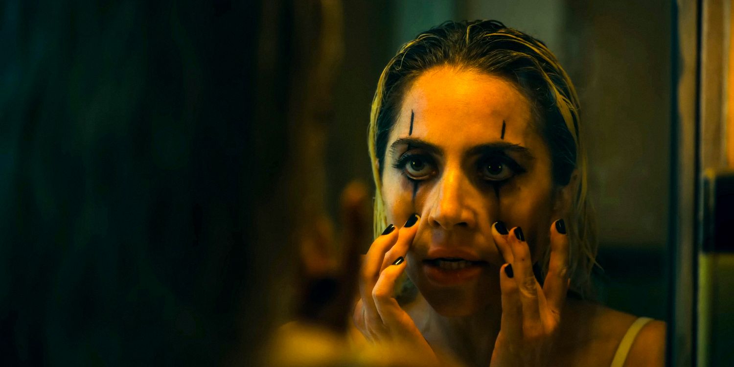 Harley Quinn (Lady Gaga) looks at her reflection in the mirror while applying harlequin-style makeup in Joker: Folie à Deux