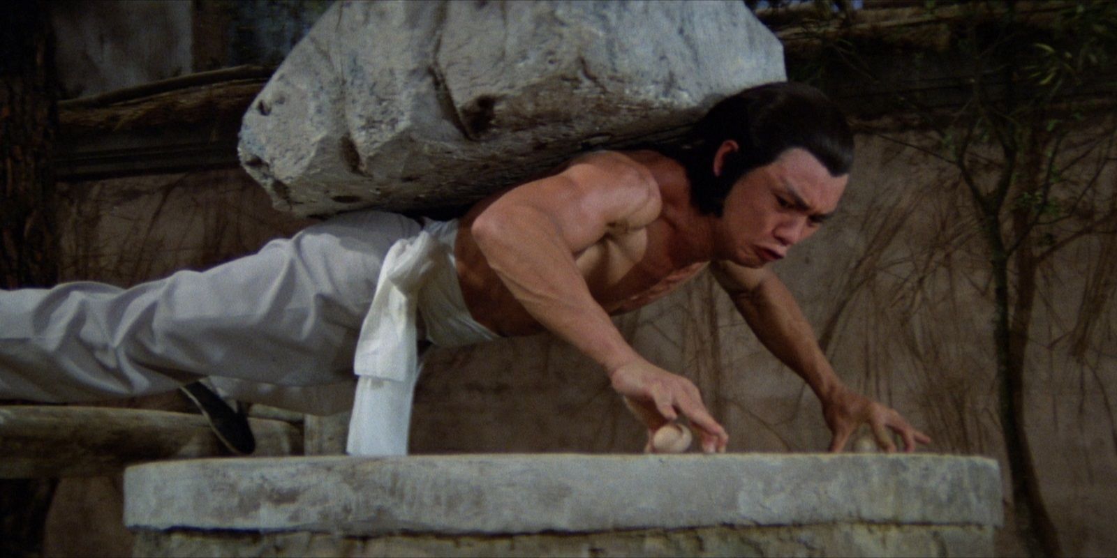 Lo Mang treinando com uma pedra nas costas em Invincible Shaolin
