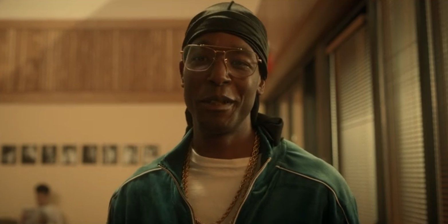 Luke James as Edmund Gaines wearing a green track suit, glasses, and durag in Them: The Scare