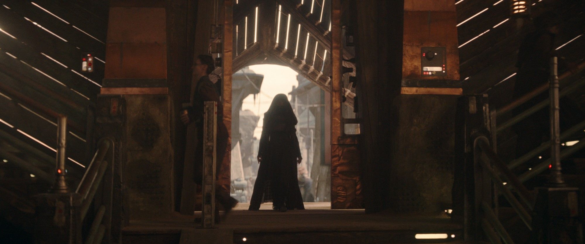 Uma figura, provavelmente Mae (Amandla Stenberg), está na porta de um prédio em Star Wars: The Acolyte