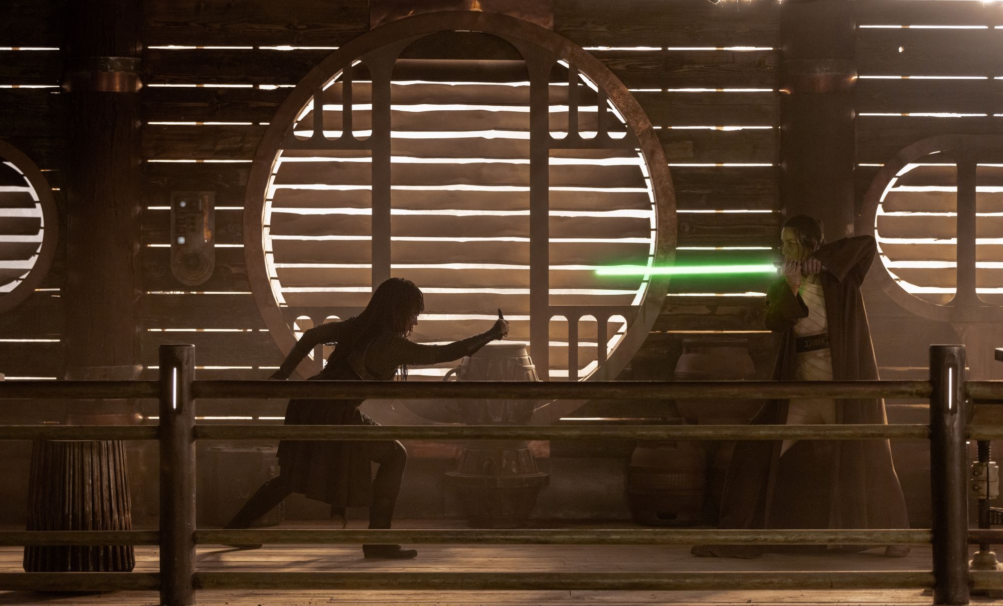 Mae (Amandla Stenberg) estende o braço enquanto luta contra Indara (Carrie-Anne Moss), que empunha um sabre de luz verde em Star Wars: The Acolyte