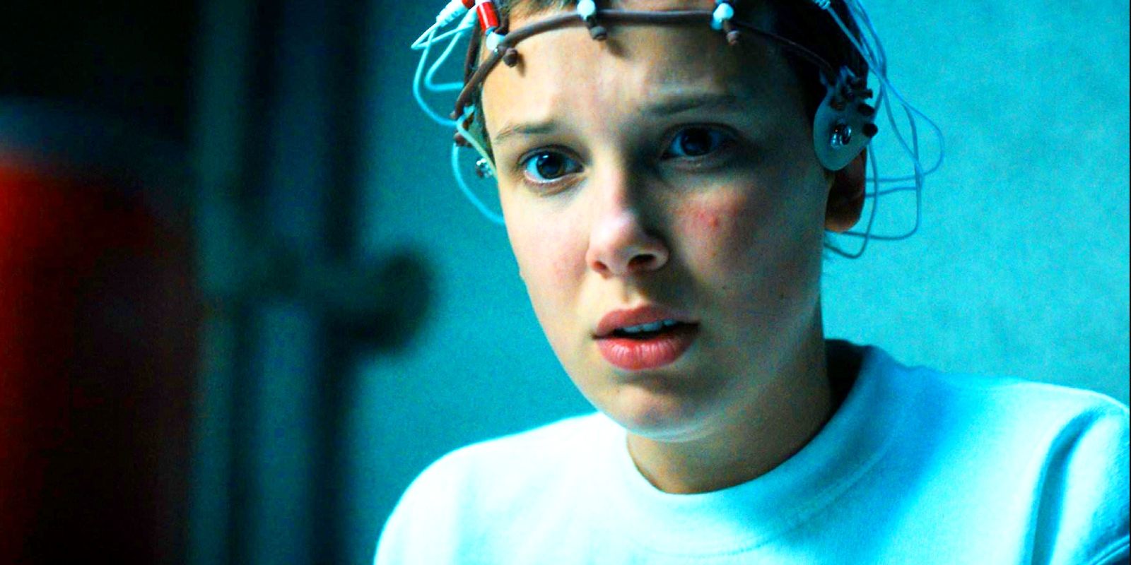 Millie Bobby Brown as Eleven looking concerned with a device on her head in Stranger Things season 4