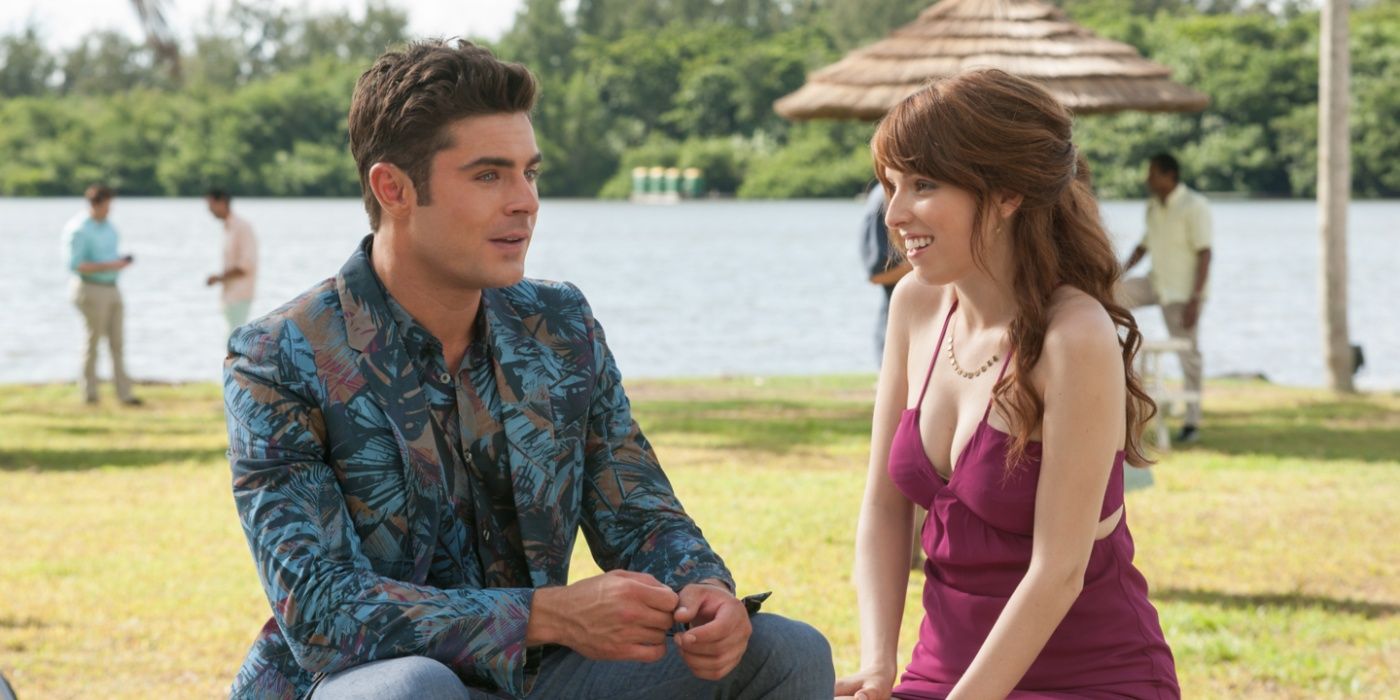 Alice (Anna Kendrick) grins at Dave (Zac Efron) while sitting by a lake in Mike and Dave Need Wedding Dates