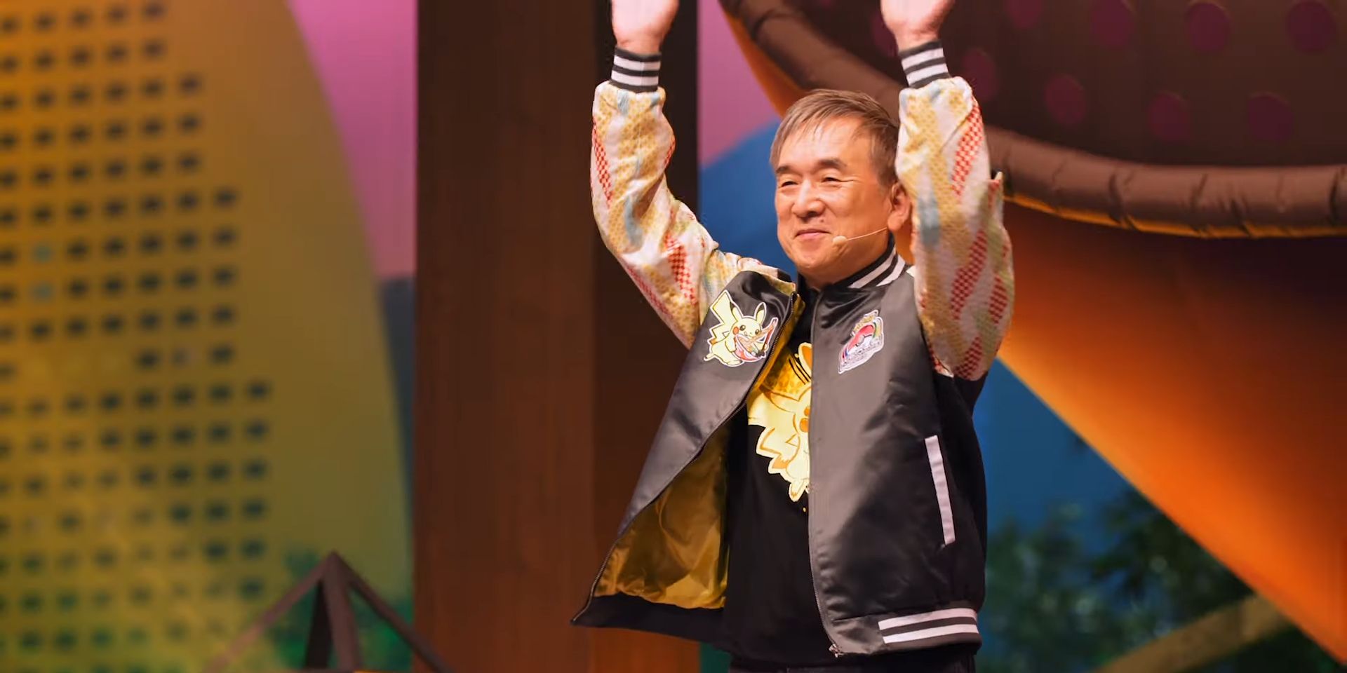 Tsunekazu Ishihara levanta os braços e sorri no Pokémon Worlds 2023.