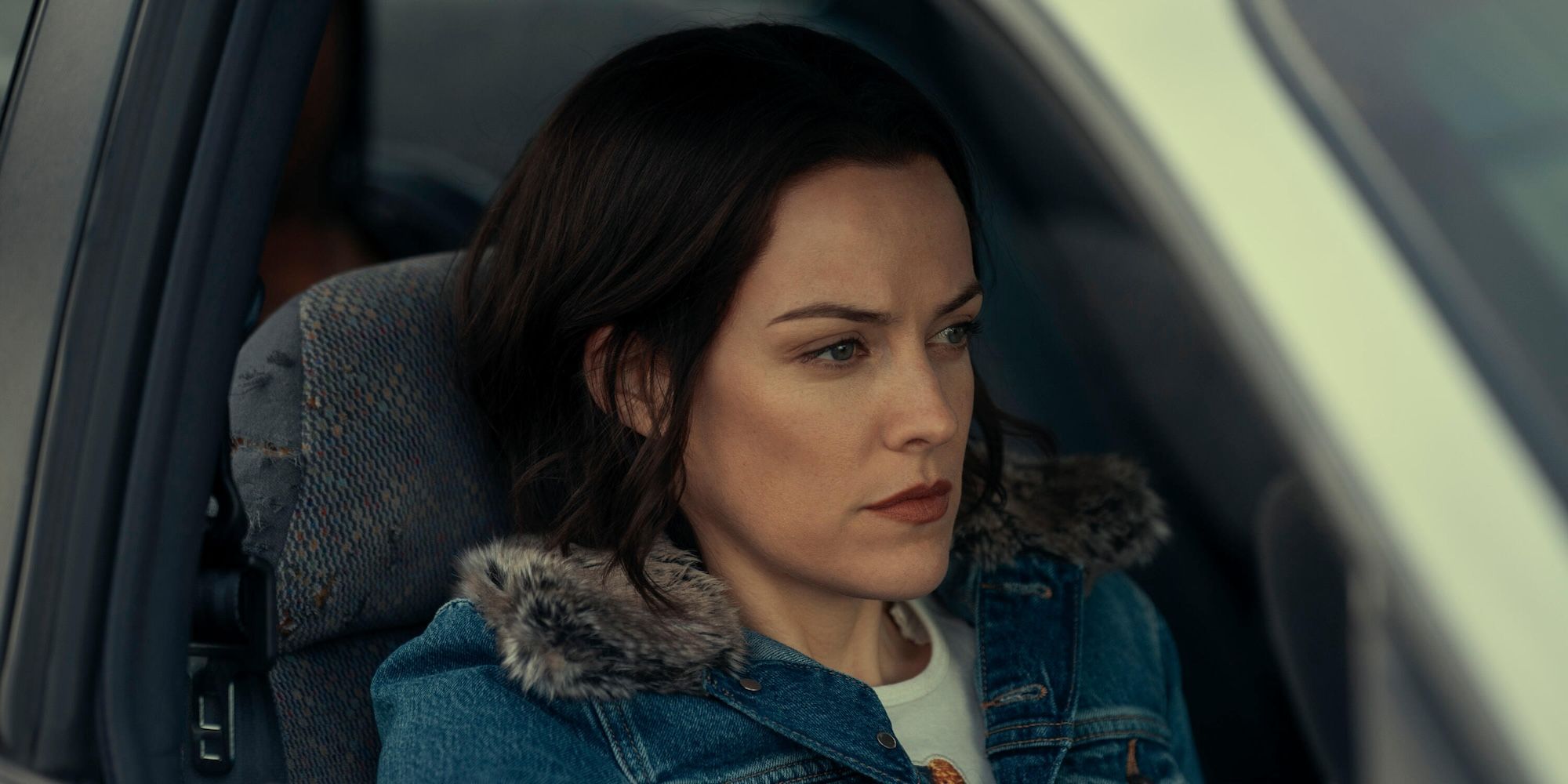 Rebecca (Riley Keough) sits in a car and stares ahead in Under the Bridge