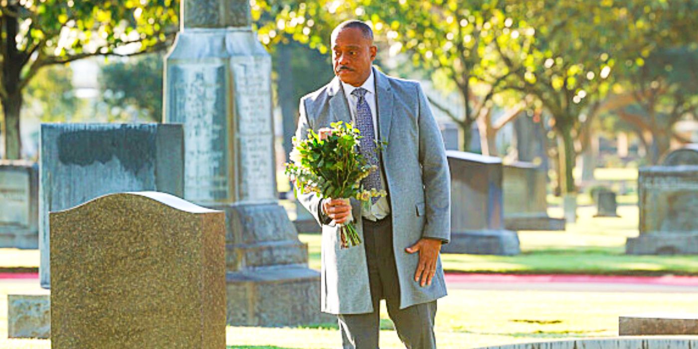 Rocky Carroll as Leon Vance holding flower at a grave in NCIS