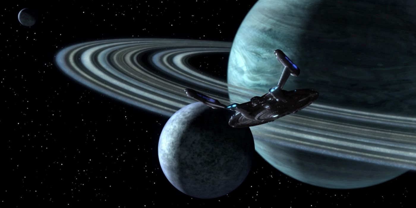 The USS Enterprise flies by a ringed planet and its moon