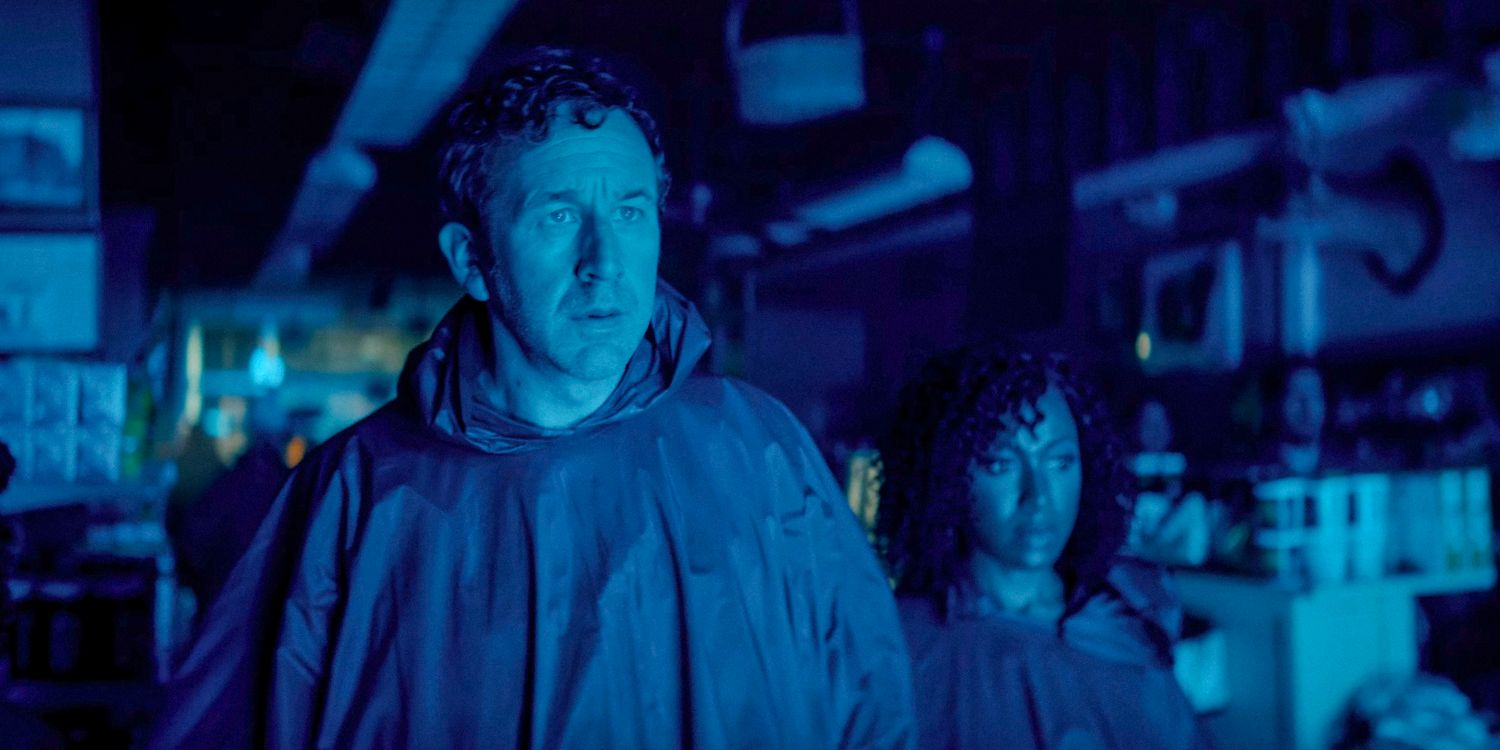 Dusty (Chris O'Dowd) e Cass (Gabrielle Dennis) parecendo surpresos ao serem iluminados por uma luz azul neon na 2ª temporada do The Big Door Prize