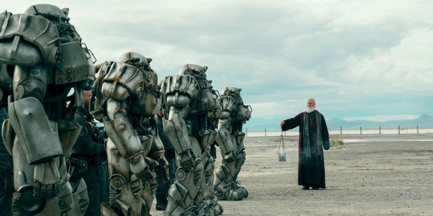 Os cavaleiros da Irmandade de Aço em seus Power Suits enquanto um clérigo passa em Fallout
