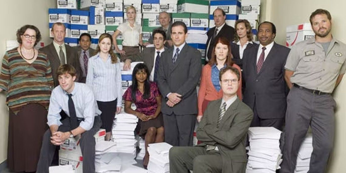 the cast of The Office standing and sitting among stacks of paper in a promotional image