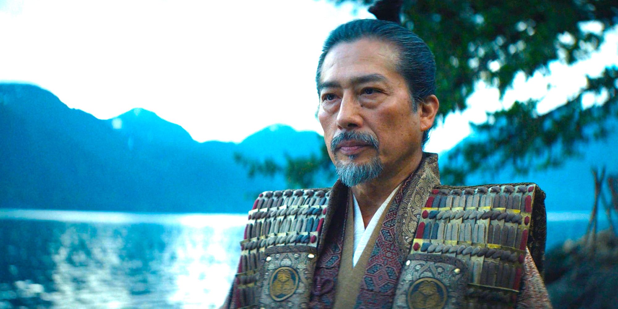 Toranaga wears a stern expression while standing next to a lake in a scene from Shogun season 1